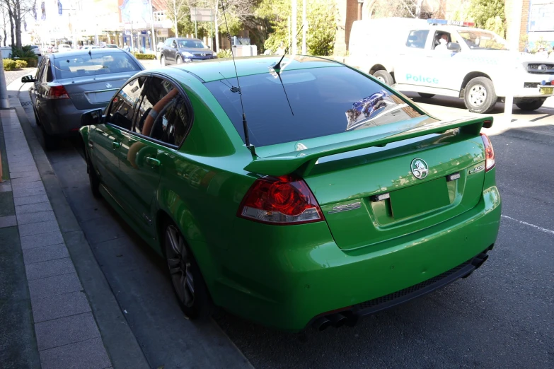 a green car with an upside down tailgate parked next to a street