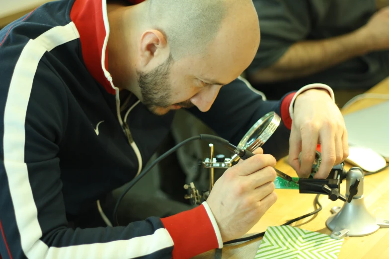 a man sitting at a table while making soing from an electronic circuit