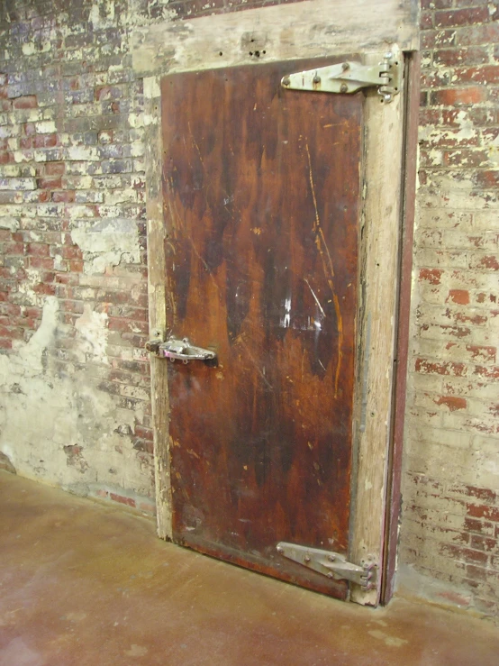 a brown door in a large wall with peeling paint