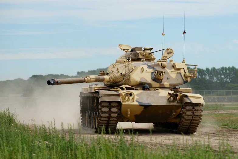 military tank moving across field near fenced area