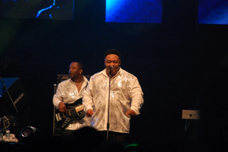 two men singing at a concert while playing guitars