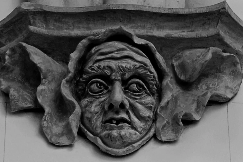 an elaborate gargoyle with a face on top of it