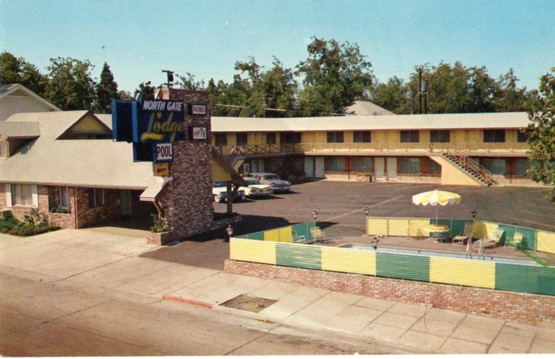 an old motel with a large swimming pool and lots of trees