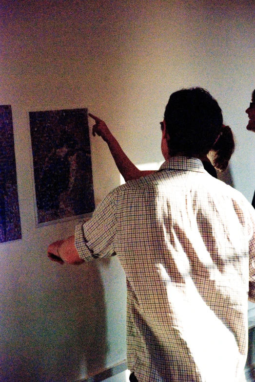 a man and woman are looking at a painting on the wall