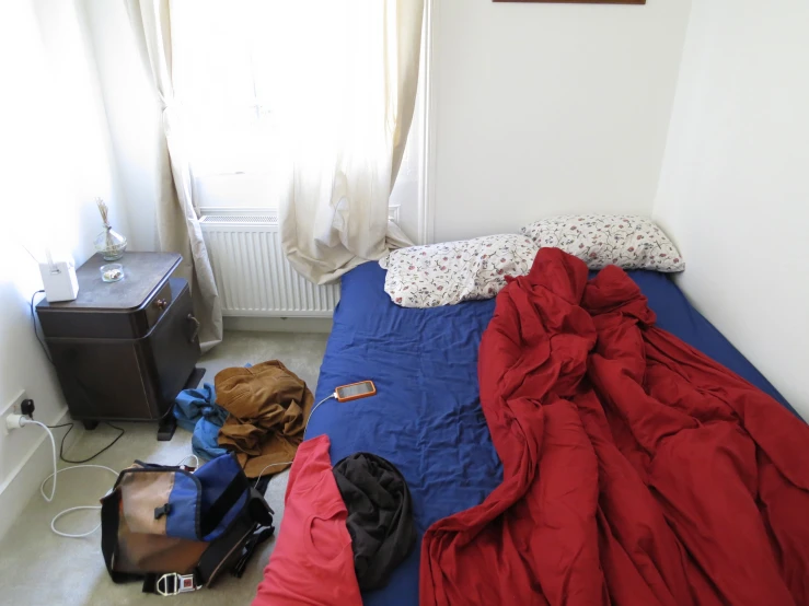 a bedroom with many blankets and backpacks on the floor