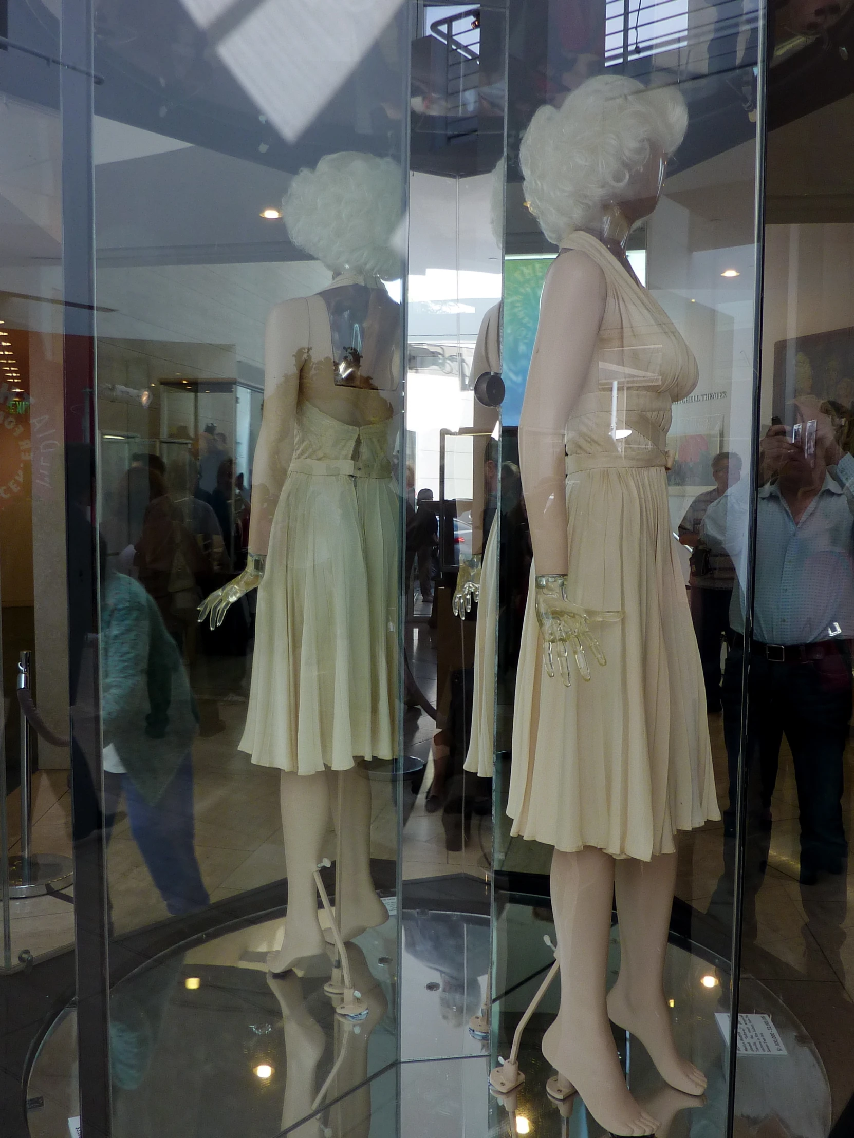 a couple of womens dresses sitting on display in front of a glass enclosure
