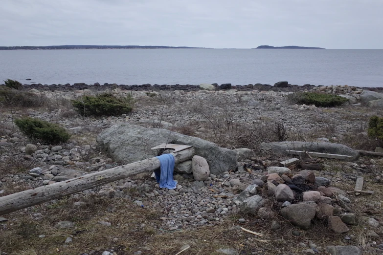 there is a blue robe on the rocks near the water