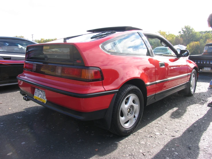 a red car parked next to a lot full of other cars