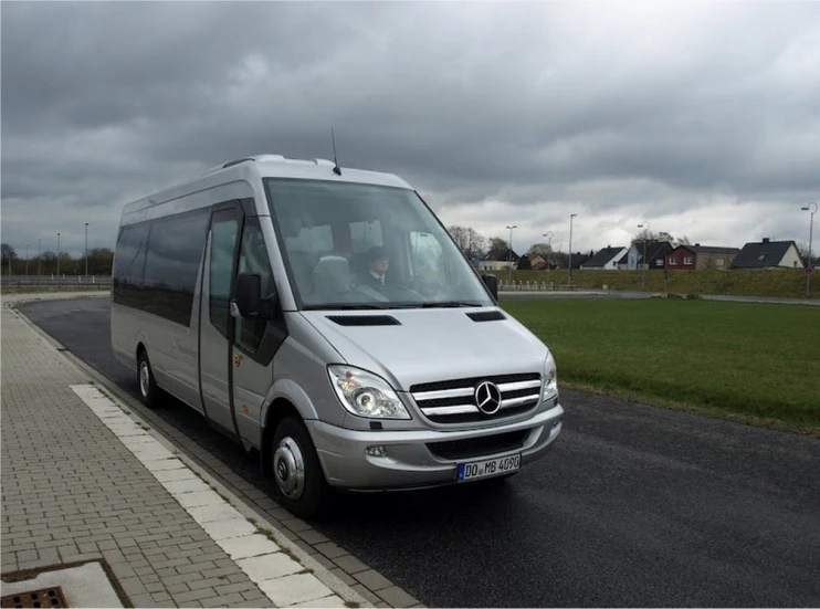 a grey van driving down the road under a cloudy sky