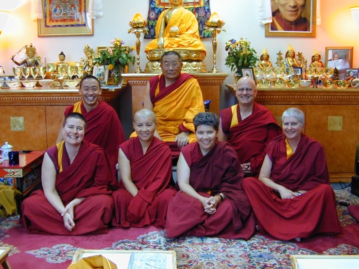 eight monks in meditation robes posing for a po