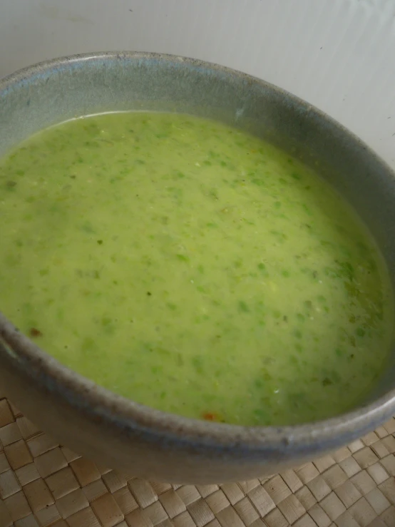 bowl of green soup sitting on top of a counter