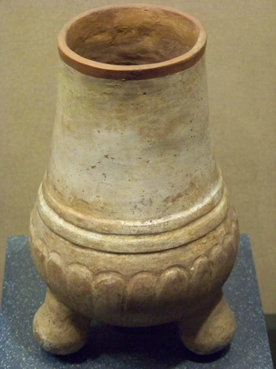 a tall ceramic vase with carved designs on it's base