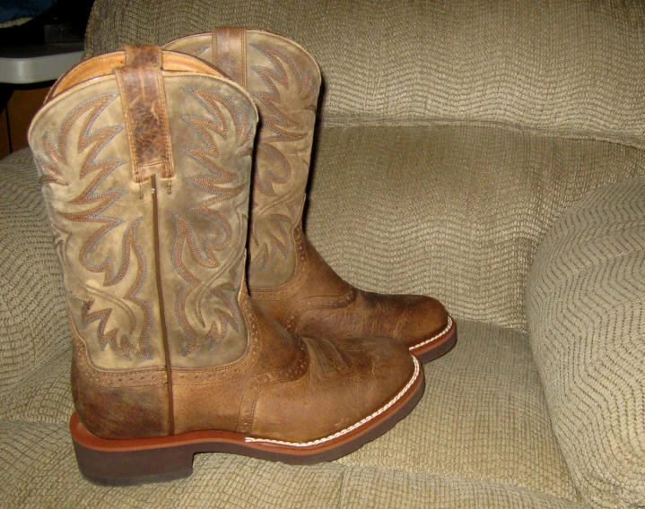 a pair of cowboy boots sit on top of the armrest