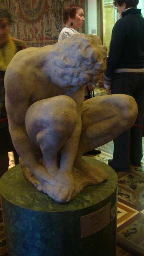 two women stand behind a statue in a lobby