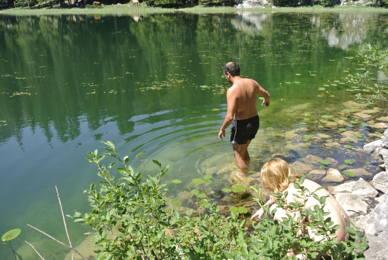 a man standing in water next to a child