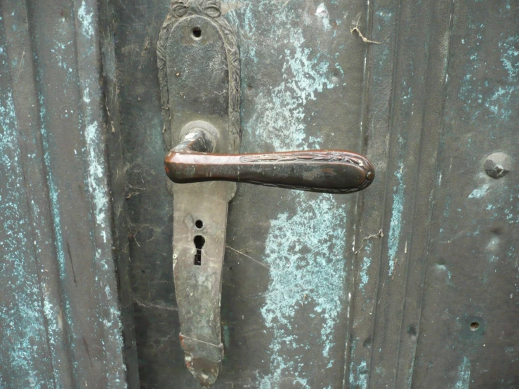 a door handle and latch on a weathered iron door