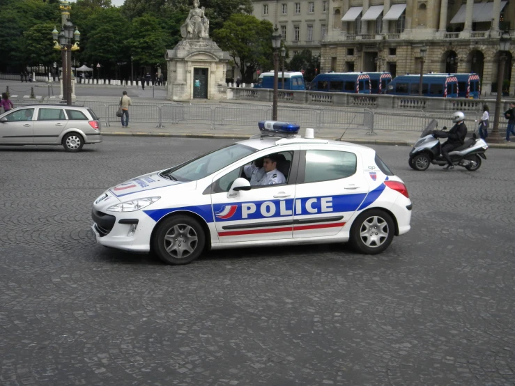 an adult driving a police car on a street