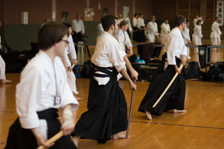 men with wooden sticks in their hands in a gymnasium