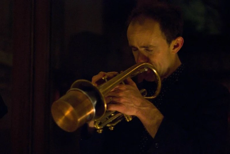 a man is holding a trumpet and wearing a black shirt