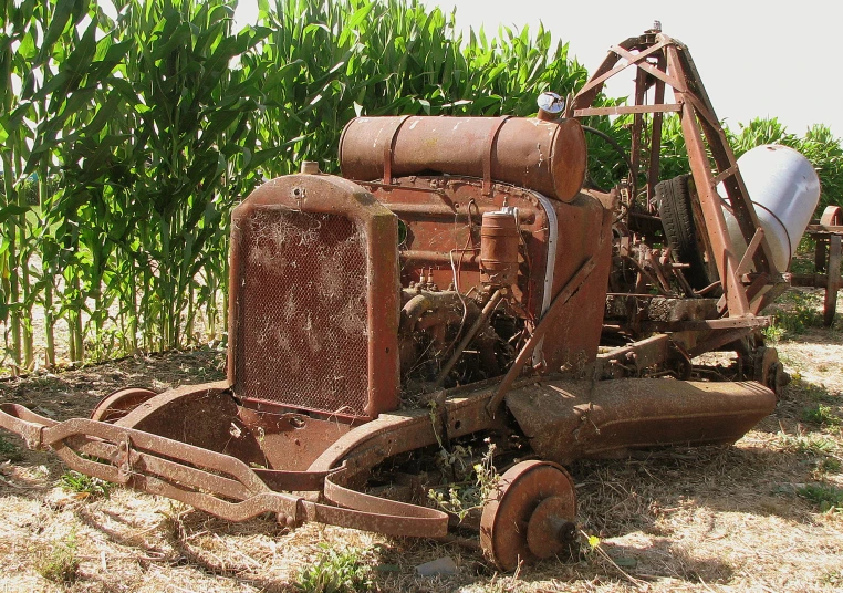 an old farm tractor sits abandoned in the corn field