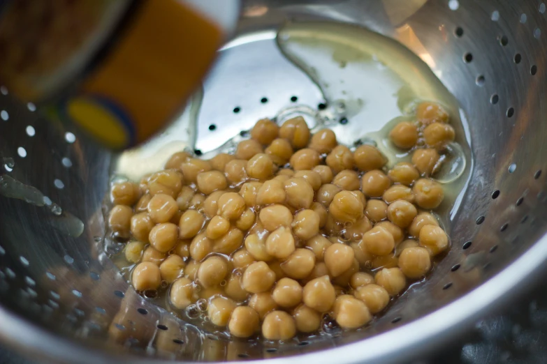 some beans are being strained in a metal bowl