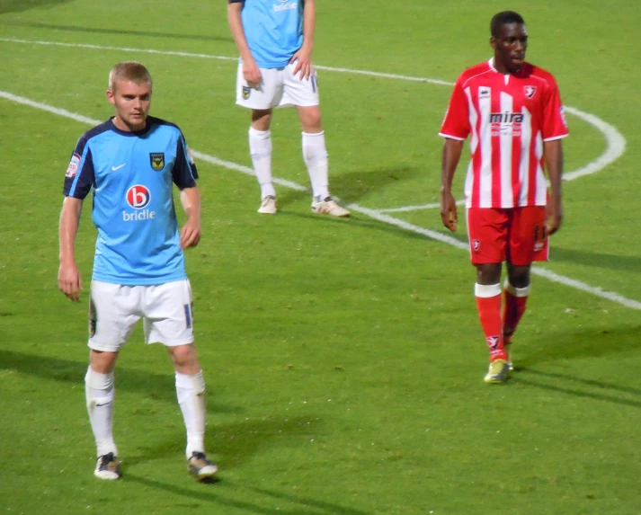 three men standing on the grass with soccer balls