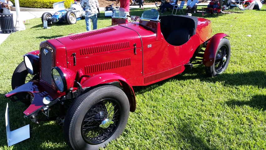 an old time red car parked on the grass