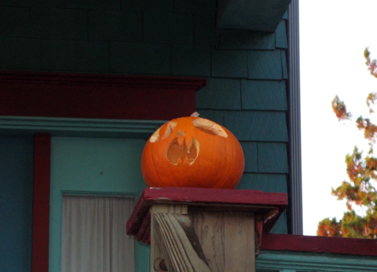 an orange pumpkin sitting on top of a wood post