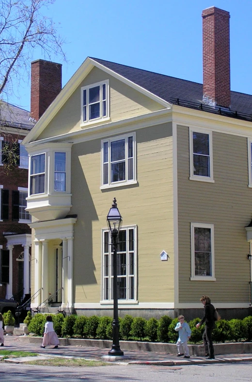 a group of people walking on the sidewalk in front of a home