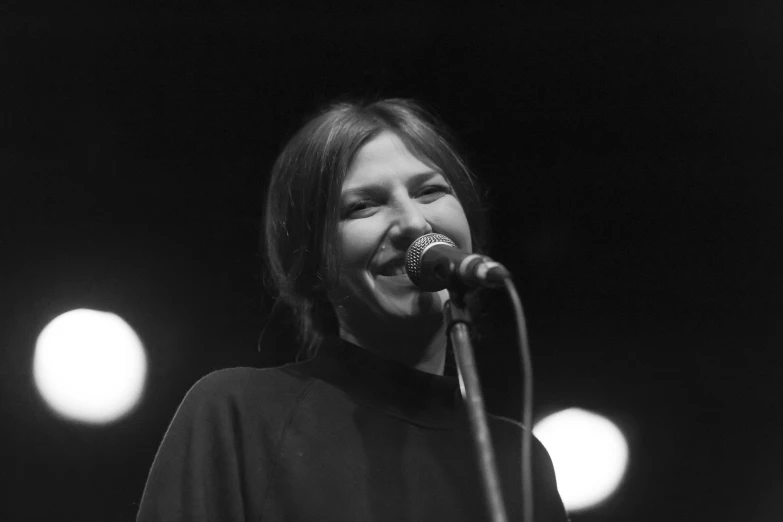 a female singing into a microphone in a black and white po