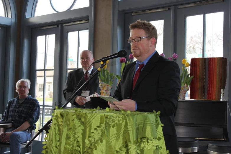 a man standing at a podium while holding a microphone