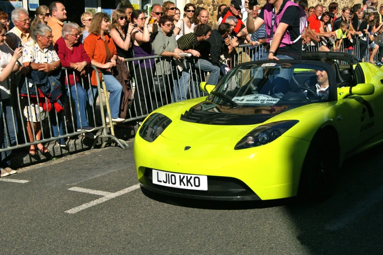 a crowd of people standing next to a yellow sports car