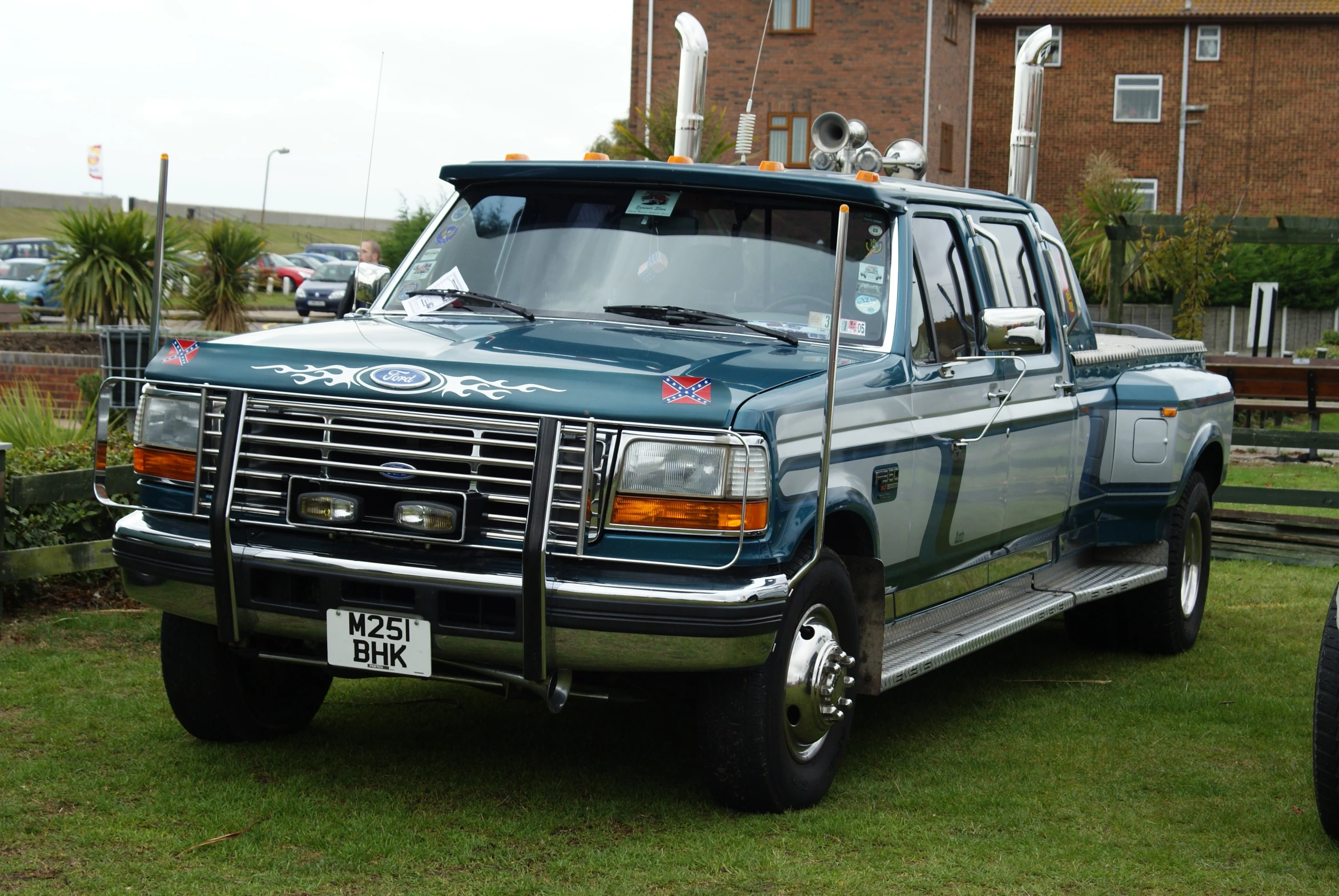 an old truck sits in the grass near a building