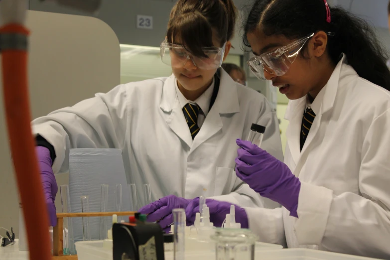 two girls in lab coats examining soing