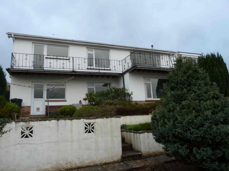 a white two story house sitting next to a cement wall