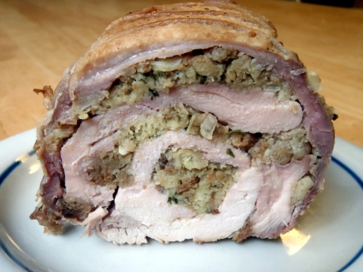 a ham roll with stuffing on a white plate
