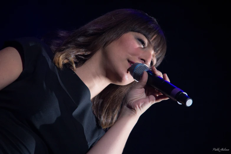 a woman singing with a microphone while wearing black