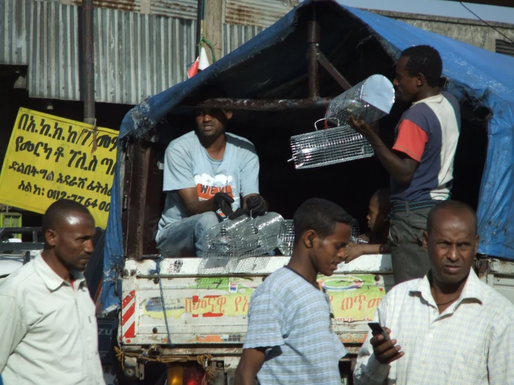 men gather to inspect items in a truck bed