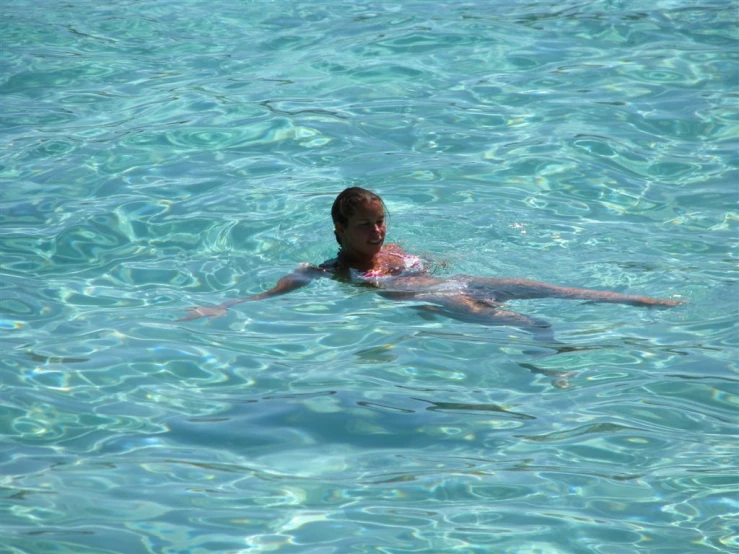 the person has one hand on his chest as he swims in the blue water