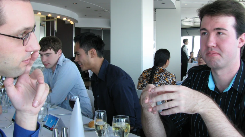 the men are sitting at the bar with drinks in their hands