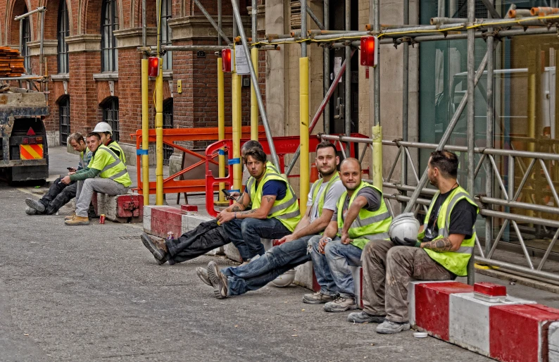 a group of construction workers sitting on the side of a road