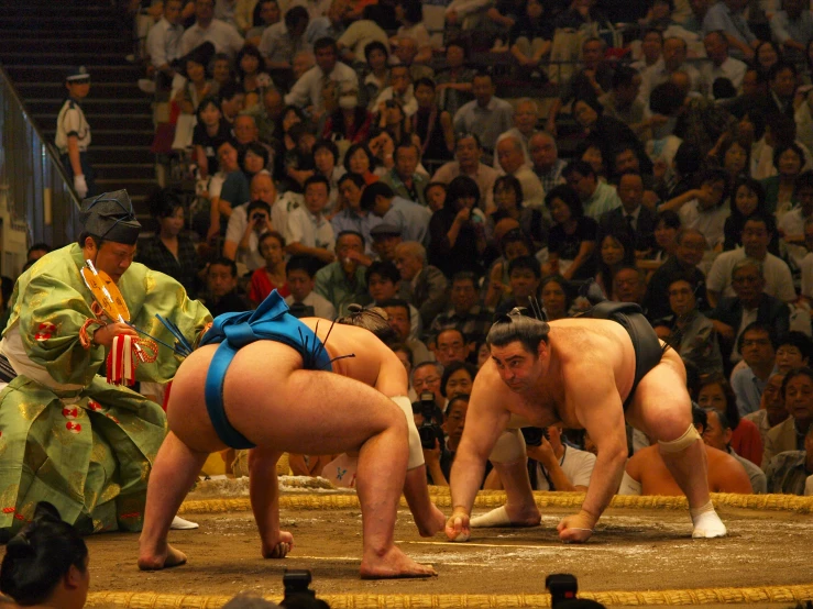 sumo wrestlers are being watched by a crowd