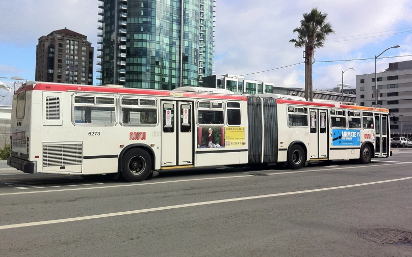 a transit bus sitting on the side of a street in front of tall buildings