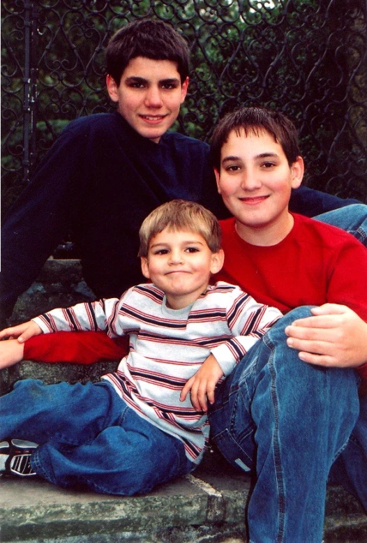 two young men and a little boy sitting on steps