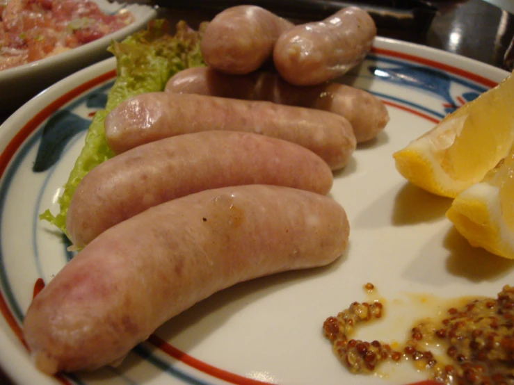 several sausages sit on a plate with slices of lemon, lettuce and other foods