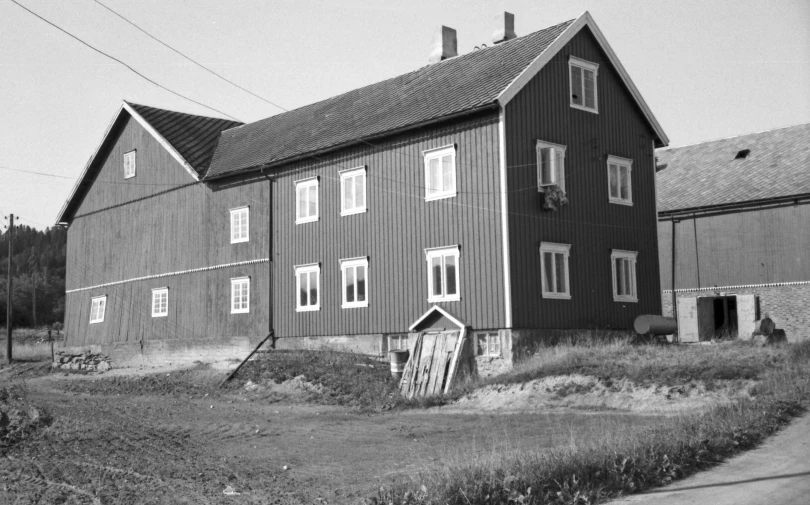 the old barn with several windows sits in a grassy field