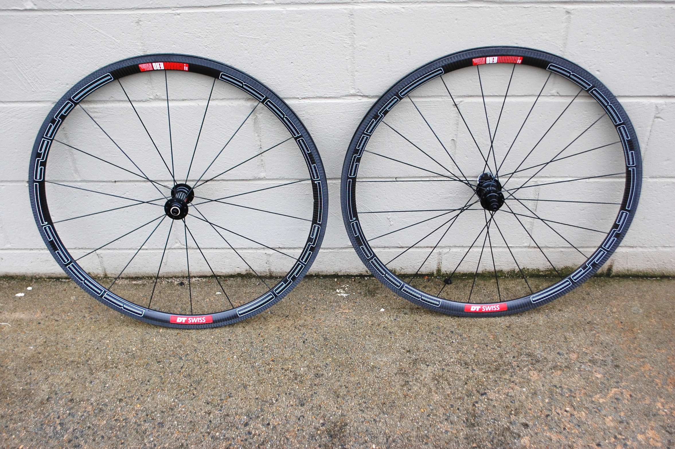 pair of bicycle wheels laying against wall against building