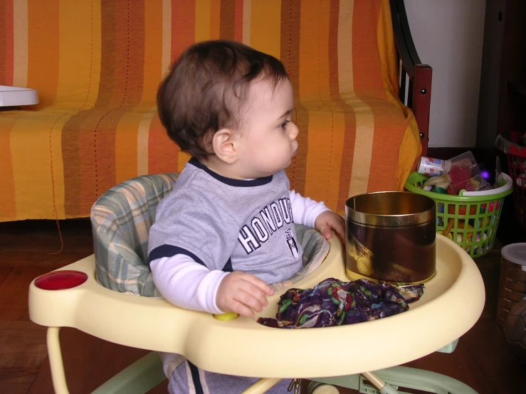 a baby sitting in a high chair and looking at soing on the table