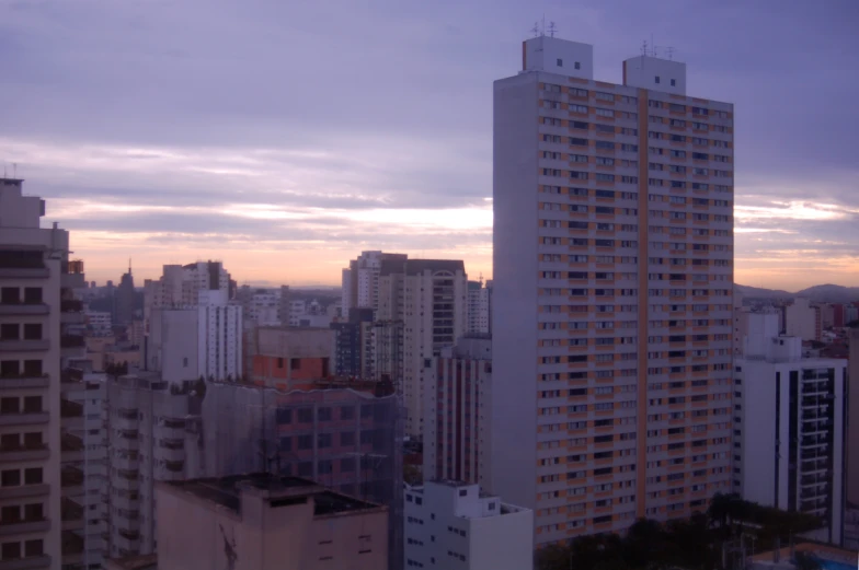 a city skyline during the day with the moon visible