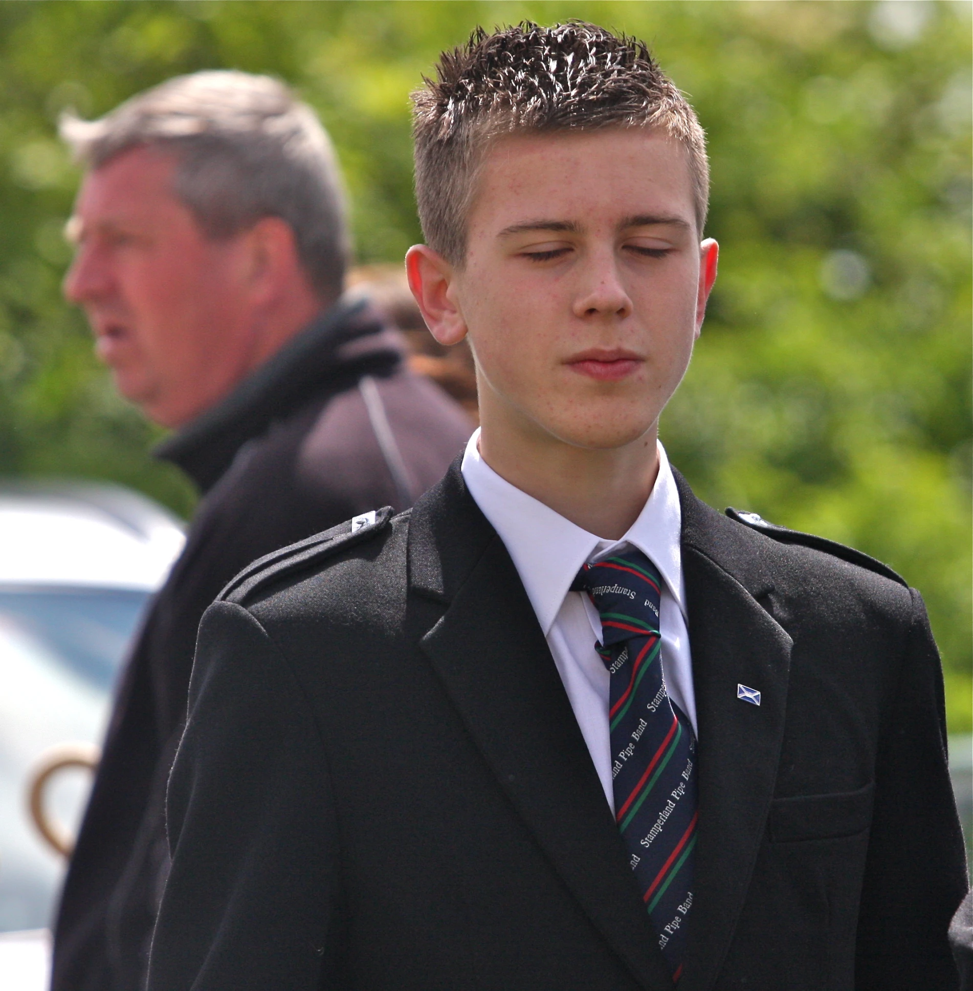 boy in jacket and tie standing next to another person